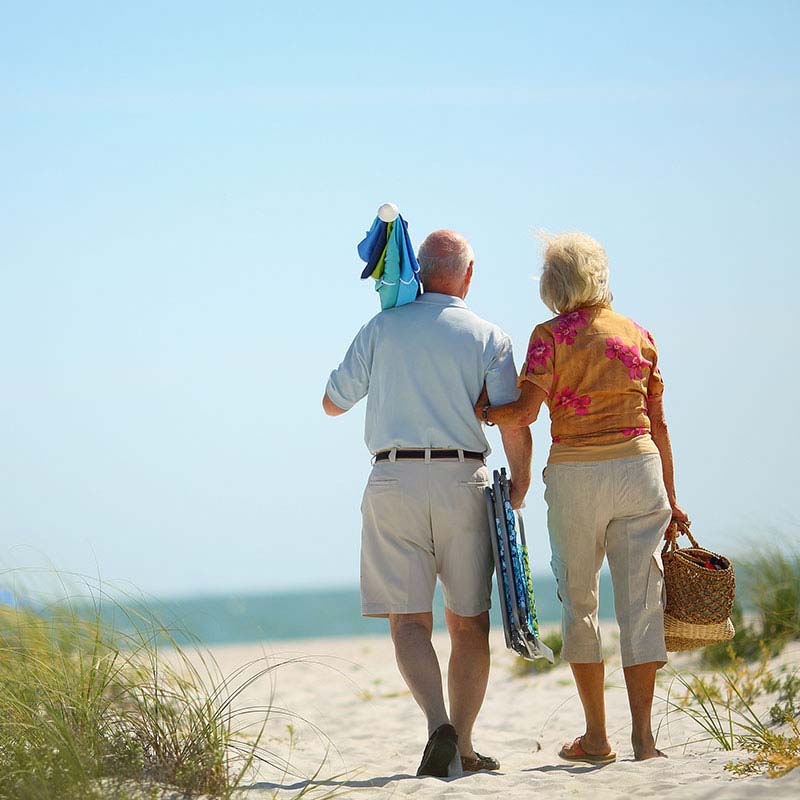 elderly couple walking to the beach